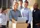 a small group of warehouse staff gather around a laptop